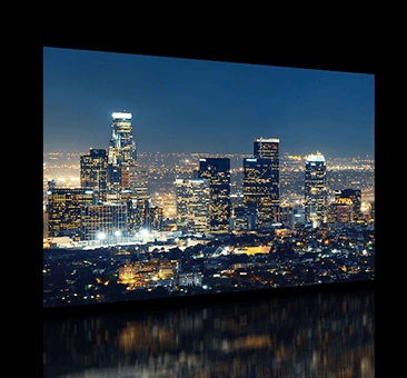 En la pantalla del televisor se ven los edificios altos de la ciudad por la noche.