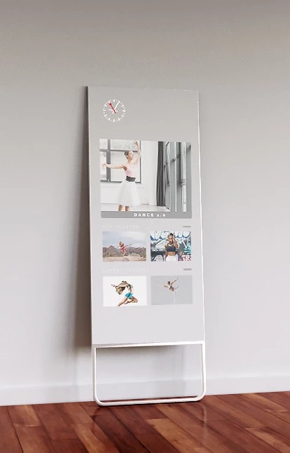 QAIO Flex a fitness mirror lean on wall mount with a video of women dancing on the screen in a room.