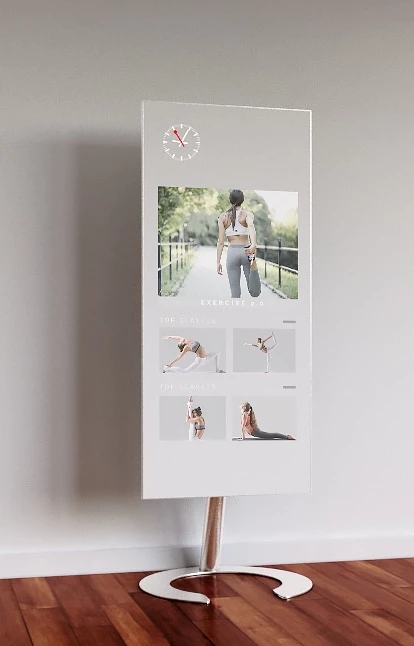 Stand alone mounted QAIO Flex fitness mirror with a woman working out shown on the screen.