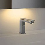 Sink faucet with a sensor night light gleaming behind a mirror.