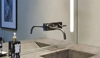 A bathroom shows the faucet and a light cut out on the mirror.