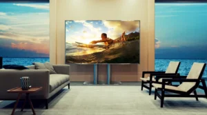 A modern living room at dusk with a large cinema TV displaying a surfing scene.